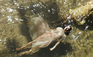 Imagem do filme com fundo de água e uma mulher ao centro flutuando sobre a água. 