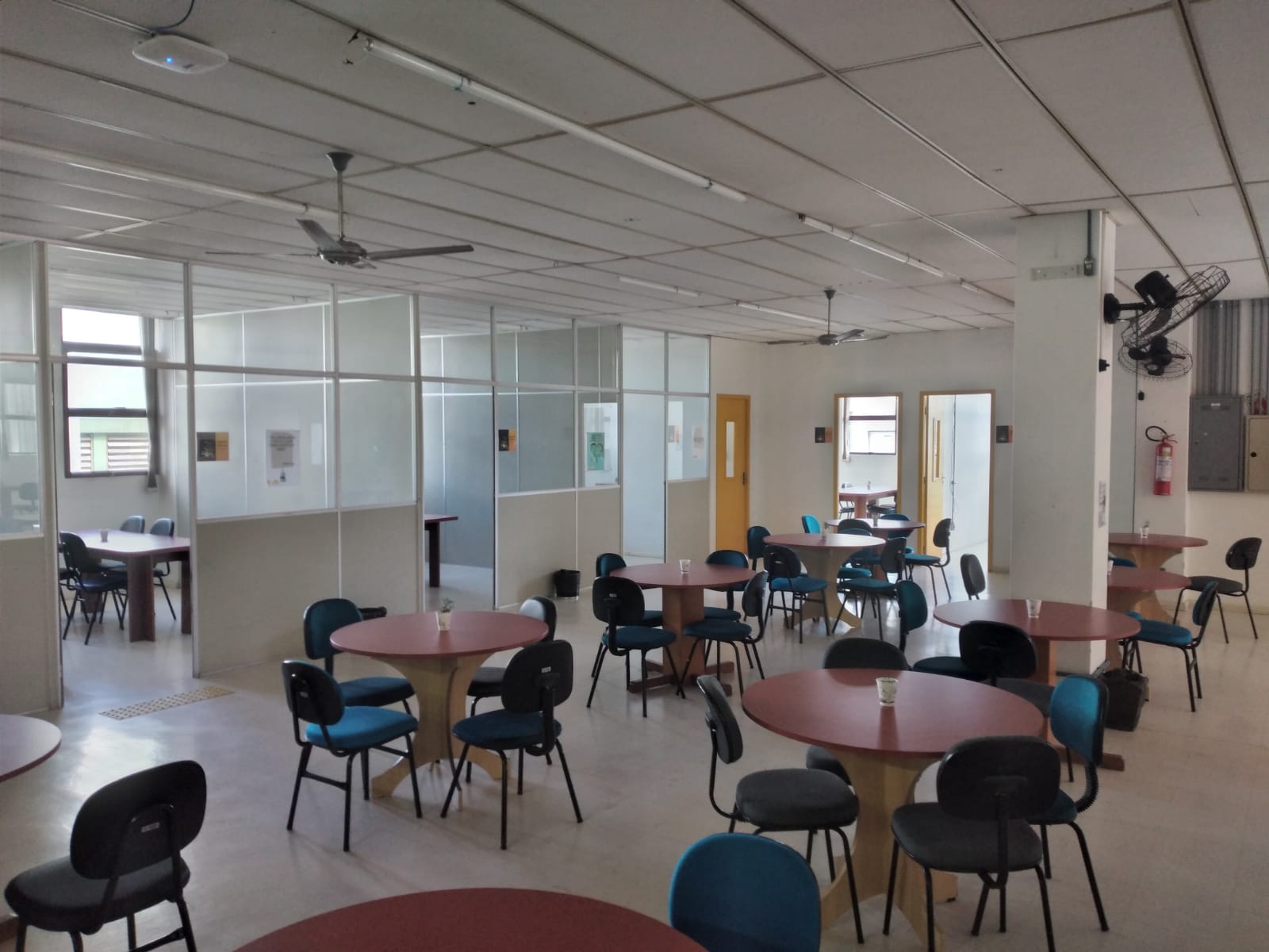 Foto do salão de estudos da Biblioteca Setorial da Área Acadêmica da Saúde, onde aparecem diversas mesas e cadeiras e salas de estudo em grupo.