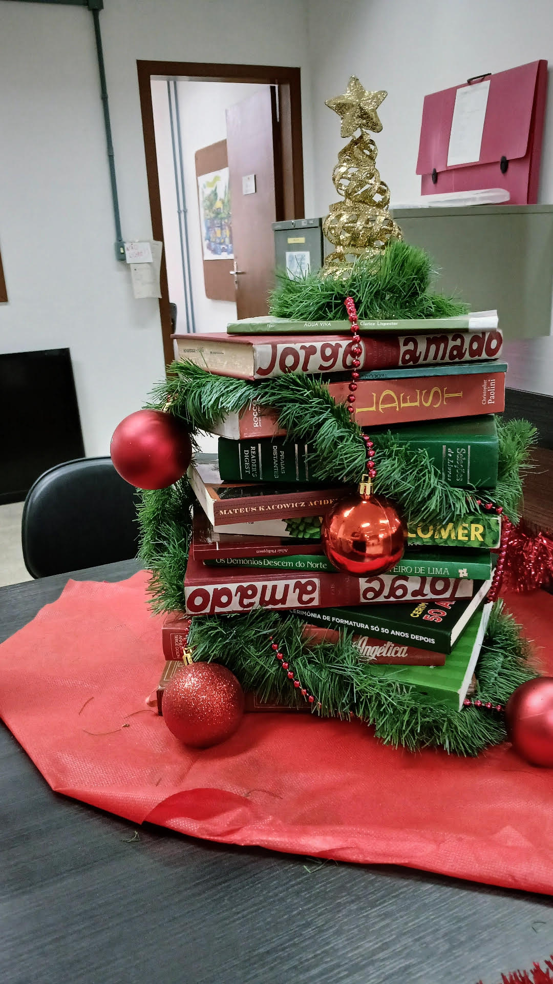 Imagem de uma árvore de Natal feita de livros da biblioteca, para decorar a exposição.